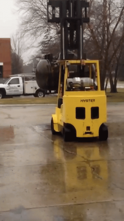 Forklift holding a 400 gallon steel tank for a drop test.